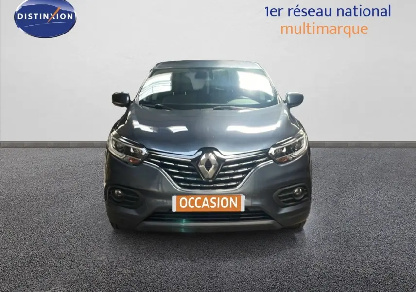 Vue avant d’un Renault Kadjar gris titanium metal avec calandre chromée et phares LED allumés sur fond neutre.