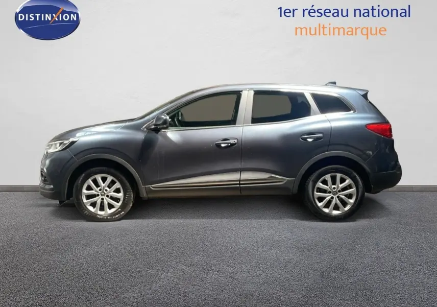 Profil droit d’un Renault Kadjar gris titanium métal 2021, SUV compact avec jantes alliage et vitres teintées.