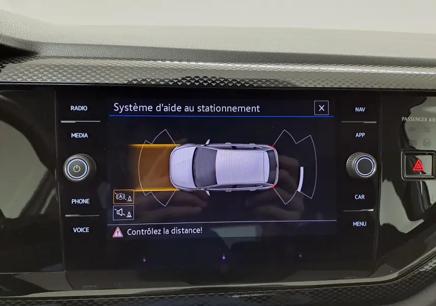 Écran central du système d'aide au stationnement de la Volkswagen Polo 2024 montrant une vue aérienne du véhicule blanc pur.