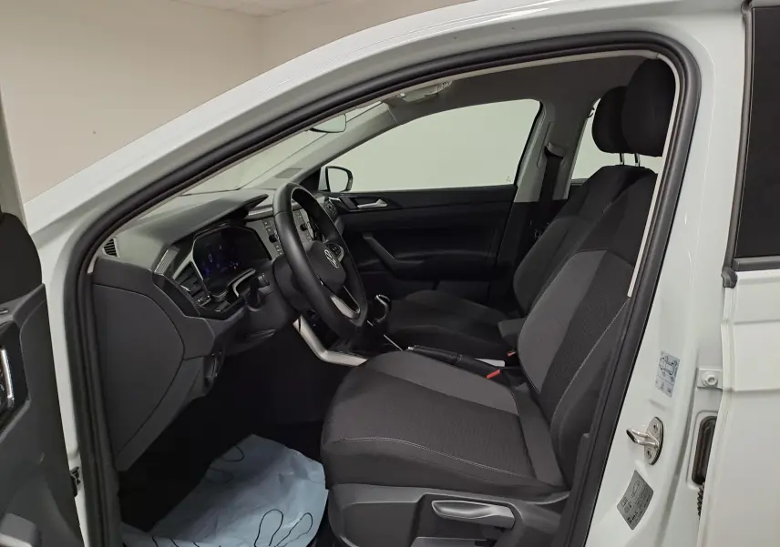 Vue intérieure côté conducteur d'une Volkswagen Polo blanc pur 2024, montrant les sièges avant et le tableau de bord.