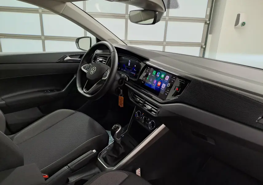 Vue intérieure côté conducteur de la Volkswagen Polo 2024 blanc pur, avec tableau de bord numérique et écran tactile central.