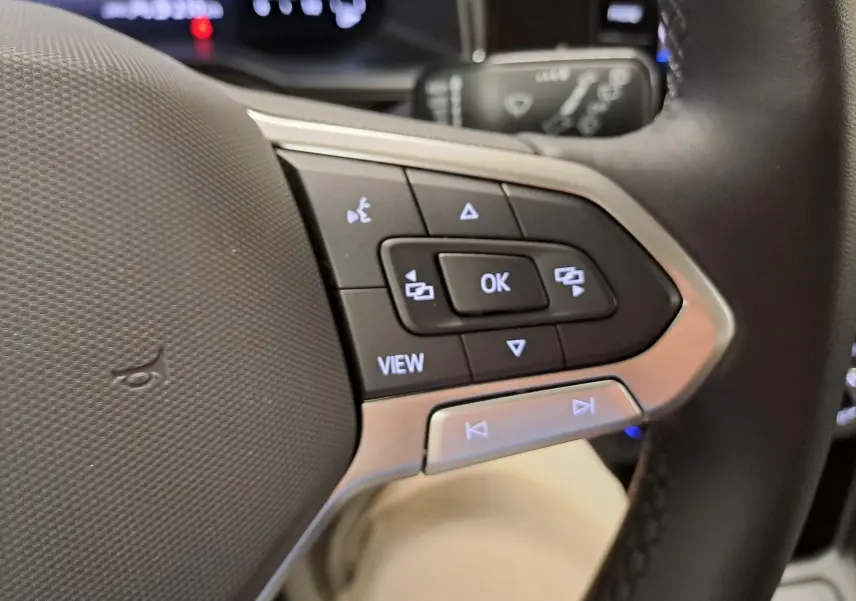 Gros plan sur les commandes multifonctions côté gauche du volant noir du Volkswagen Polo blanc pur 2024.