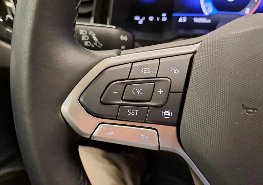 Gros plan sur les commandes de régulateur de vitesse au volant d'une Volkswagen Polo blanc pur 2024, côté gauche.