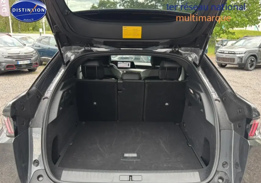 Coffre ouvert vu de l'arrière d'un Peugeot 3008 gris titane 2025, intérieur spacieux et banquette arrière rabattue partiellement.