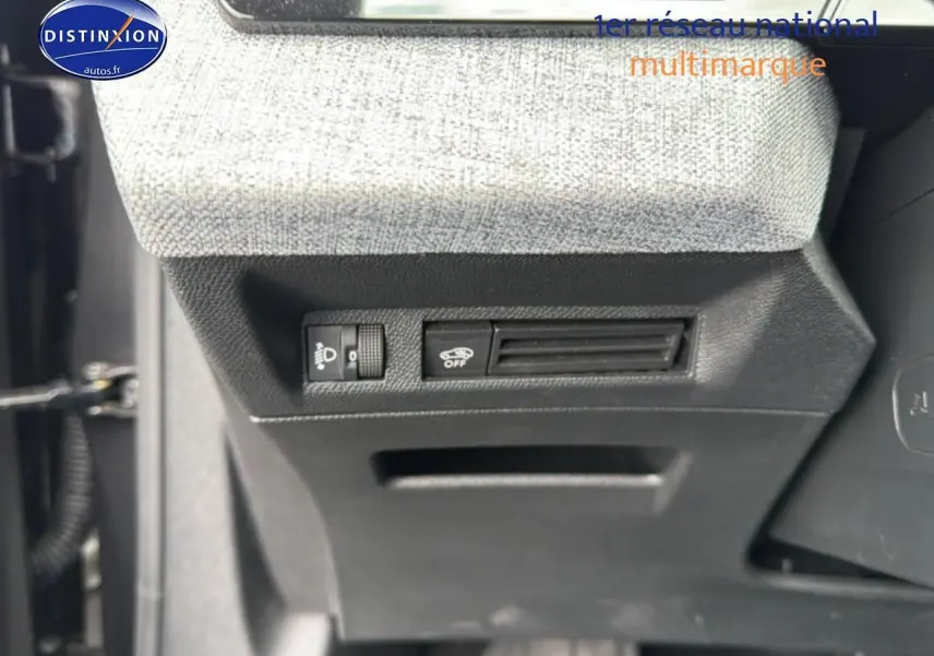Vue rapprochée des commandes sous le tableau de bord d’un Peugeot 3008 gris titane, avec réglage phares et désactivation assistance.
