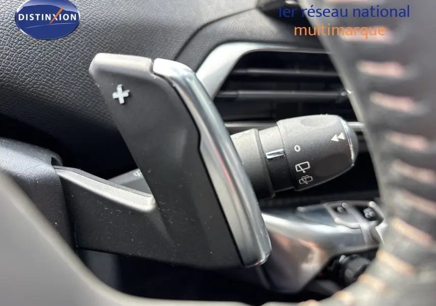 Gros plan sur la palette de changement de vitesse + du côté gauche du volant d’un Peugeot 3008 noir métal 2024 hybride.