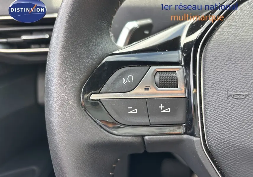 Gros plan sur les commandes du volant côté gauche du Peugeot 3008 noir métal hybride rechargeable 2024.
