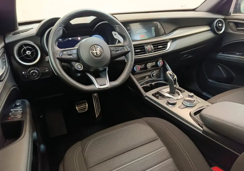 Intérieur noir de l'Alfa Romeo Stelvio 2024 vu côté conducteur, avec volant cuir et écran tactile central.