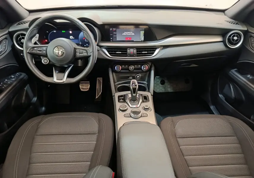 Vue intérieure avant de l'Alfa Romeo Stelvio 2.2 TD 160 AT8 Sprint 2024, tableau de bord noir avec écran tactile central.