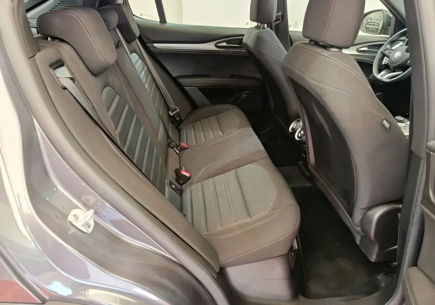 Vue intérieure côté gauche des sièges arrière gris foncé de l'Alfa Romeo Stelvio 2024 avec détails des appuie-têtes et portières.