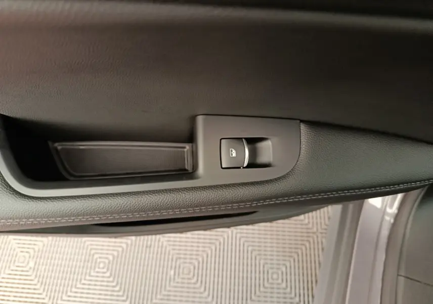 Vue rapprochée de la porte côté gauche d’un Alfa Romeo Stelvio gris foncé, avec bouton de verrouillage centralisé.