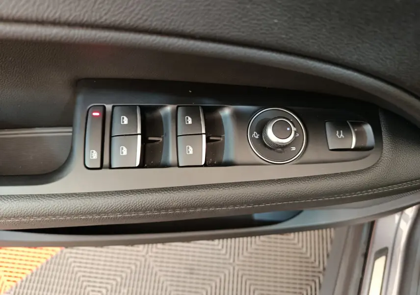 Vue rapprochée des commandes de lève-vitres et rétroviseurs sur la porte côté conducteur d'une Alfa Romeo Stelvio gris foncé.