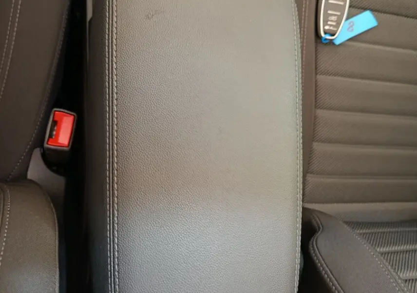 Vue plongeante sur l'accoudoir central en cuir noir et la clé de voiture posée sur le siège conducteur d'un Alfa Romeo Stelvio gris foncé.