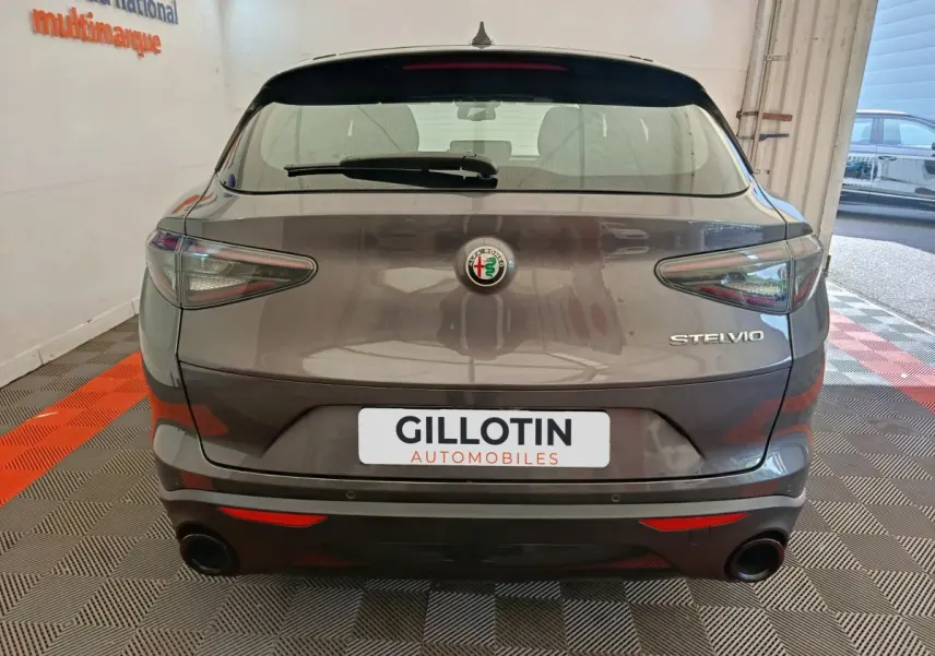 Vue arrière d'un Alfa Romeo Stelvio gris foncé 2024 avec feux LED et double sortie d'échappement noire.