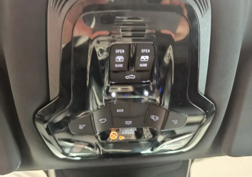 Gros plan sur la console de toit noire brillante de l'Alfa Romeo Stelvio 2024 avec commandes d'ouverture et voyants airbag.