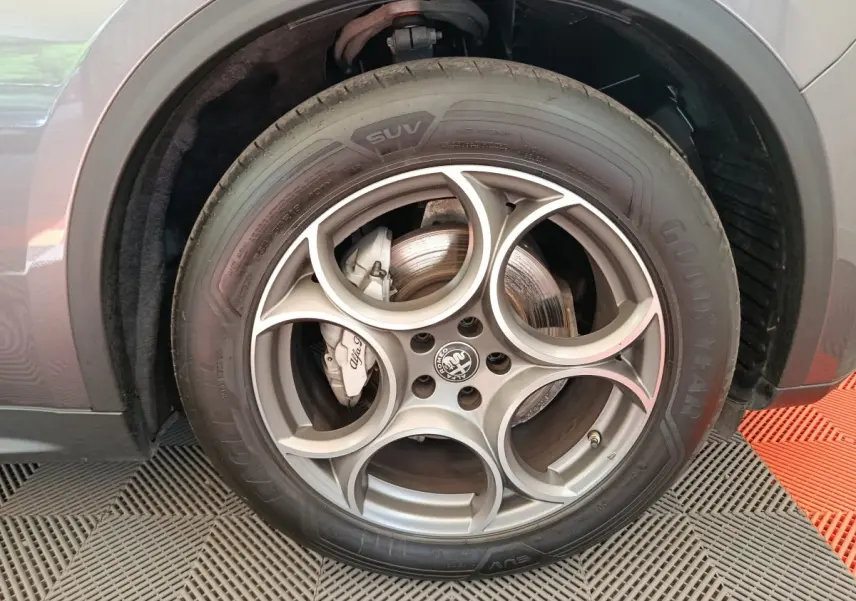 Gros plan sur la roue avant gauche gris foncé de l'Alfa Romeo Stelvio 2024 avec jante en alliage à motif circulaire distinctif.