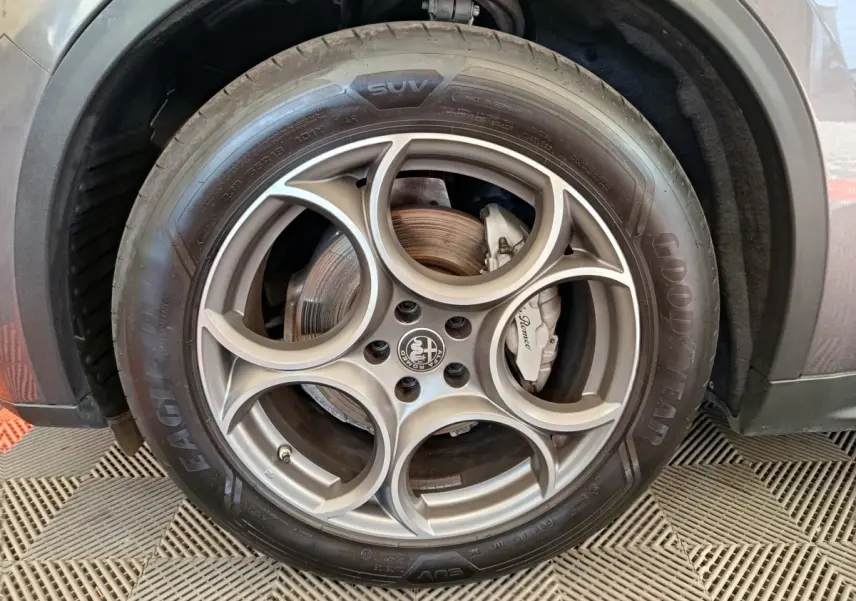 Gros plan sur la roue avant droite gris foncé d’un Alfa Romeo Stelvio avec jante en alliage et logo central distinctif.