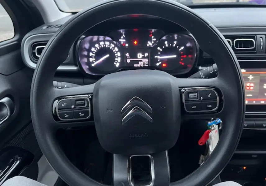 Vue centrée sur le volant noir de la Citroën C3 Shine 2023, avec tableau de bord et commandes au volant visibles.