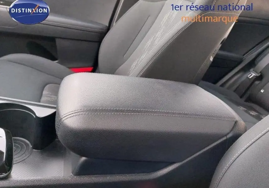 Gros plan sur l'accoudoir central en cuir noir et les sièges gris foncé à l'intérieur du Kia Sportage hybride 2024.