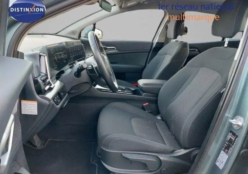 Intérieur avant droit du Kia Sportage 2024 gris Sirius Metal, sièges tissu noir et tableau de bord moderne.