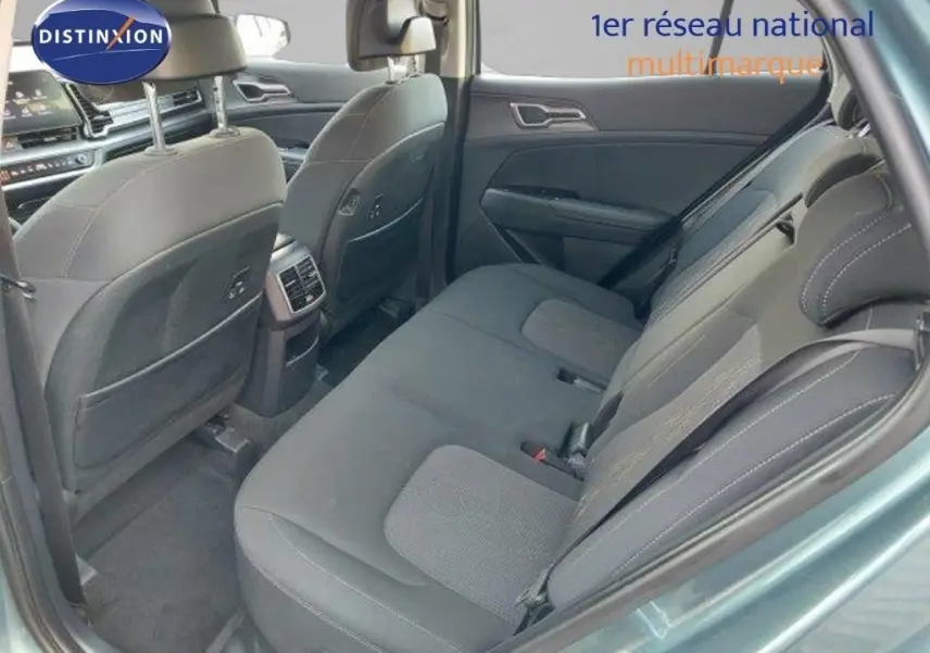 Vue intérieure arrière côté droit du Kia Sportage 2024, sièges tissu noir avec surpiqûres grises, ambiance sobre et moderne.