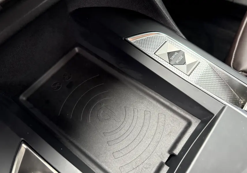 Gros plan sur la console centrale du DS3 2024 noir Perla Nera, mettant en valeur le bouton Drive Mode et le chargeur sans fil intégré.