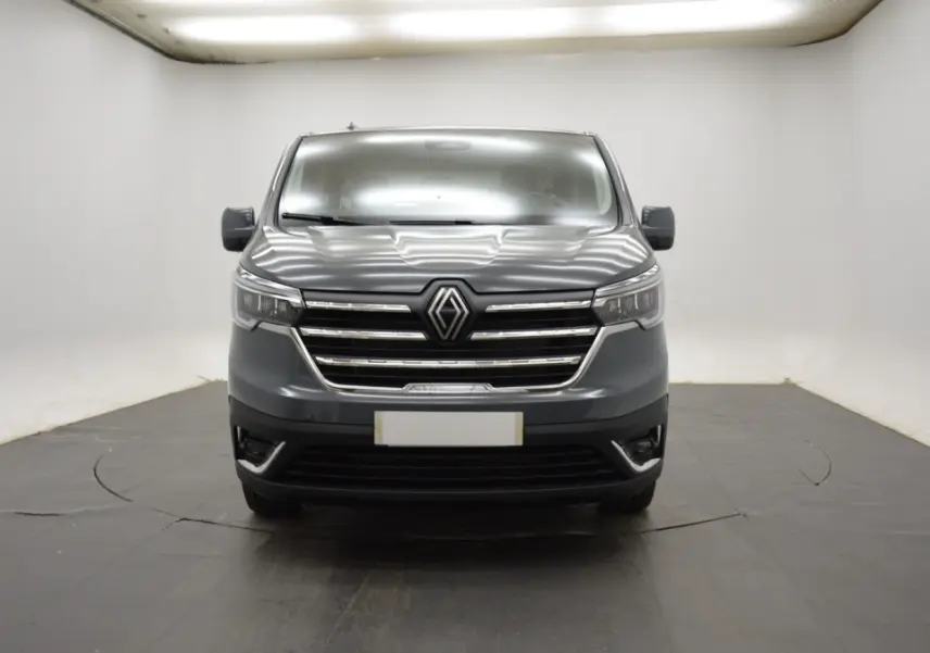 Vue frontale d’un Renault Trafic Fourgon gris clair, avec calandre chromée et logo Renault bien visible.