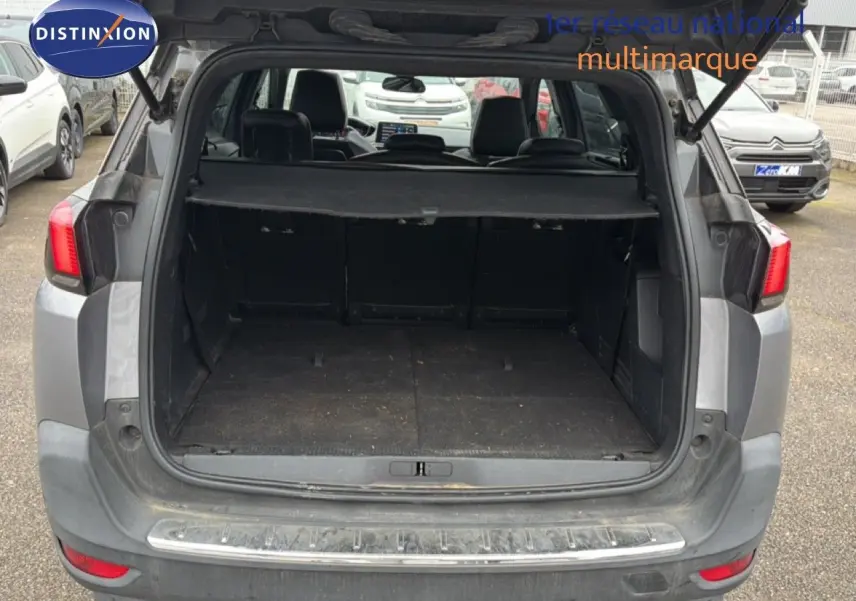 Coffre ouvert d’un Peugeot 5008 gris Artense vu de l’arrière, montrant l’espace de chargement et la plage arrière.