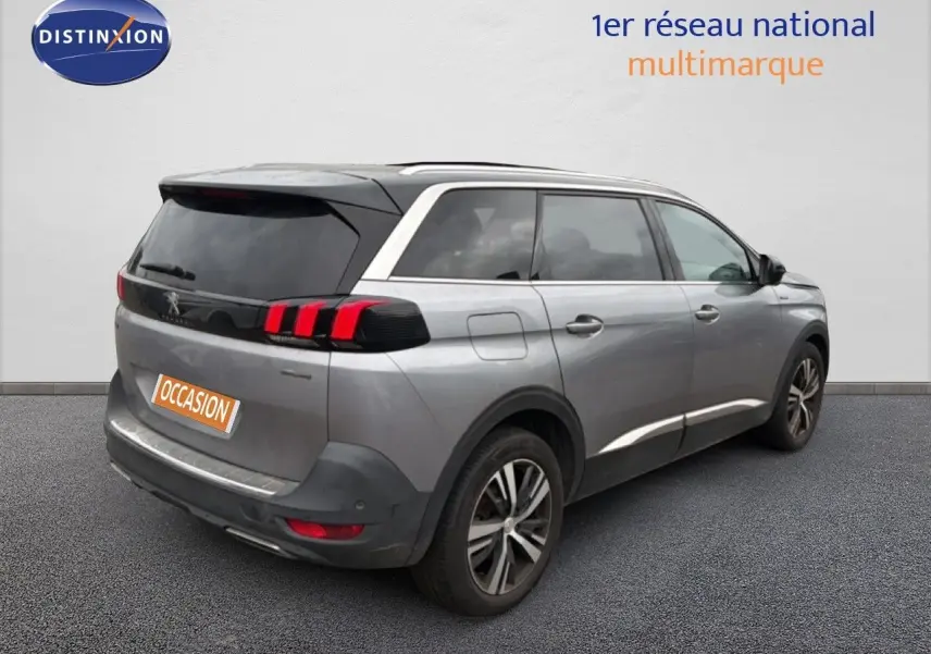 Vue 3/4 arrière droite d’un Peugeot 5008 gris Artense avec feux arrière à griffes rouges et jantes alliage bicolores.