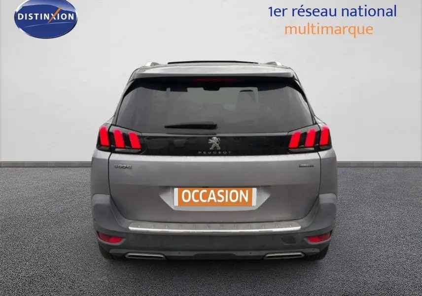 Vue arrière d’un Peugeot 5008 gris Artense avec feux LED distinctifs et double sortie d’échappement chromée.