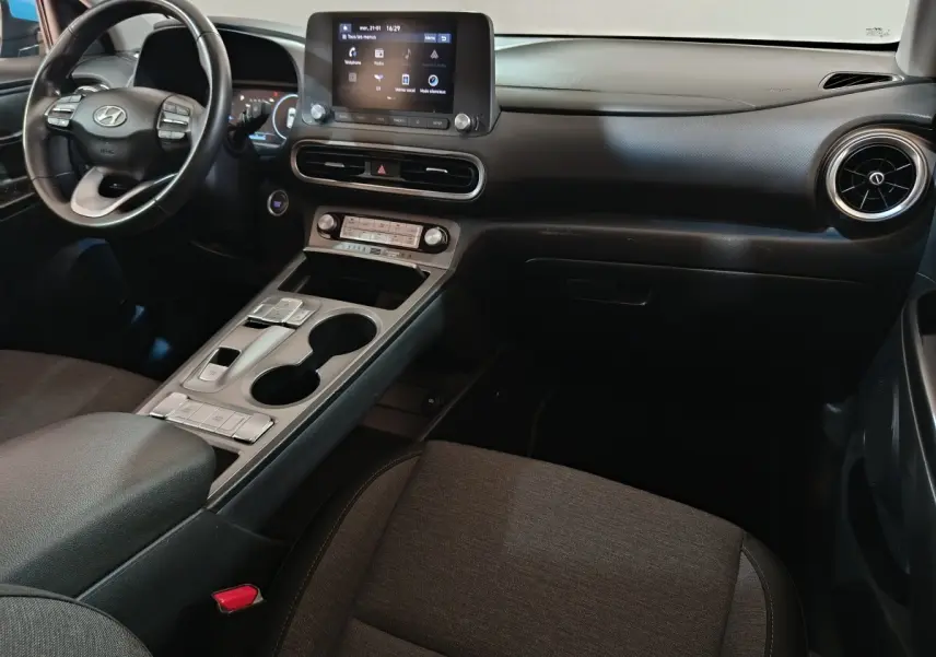 Vue intérieure du tableau de bord et console centrale de la Hyundai Kona électrique 2022 avec écran tactile et volant multifonction noir.