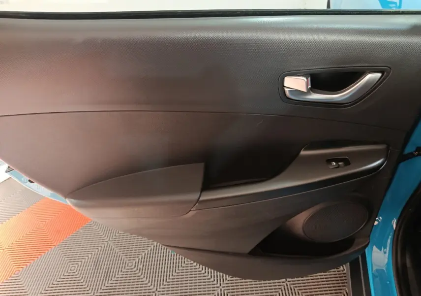 Vue rapprochée de la porte avant gauche noire avec poignée argentée du Hyundai Kona bleu électrique 2022.