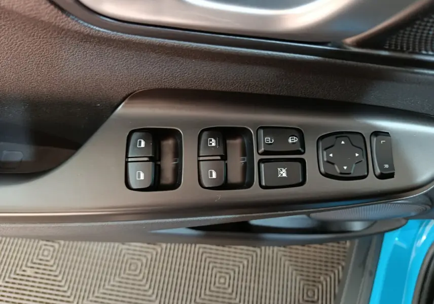 Vue rapprochée des commandes de porte côté conducteur du Hyundai Kona bleu électrique, avec boutons de réglage des vitres et rétroviseurs.