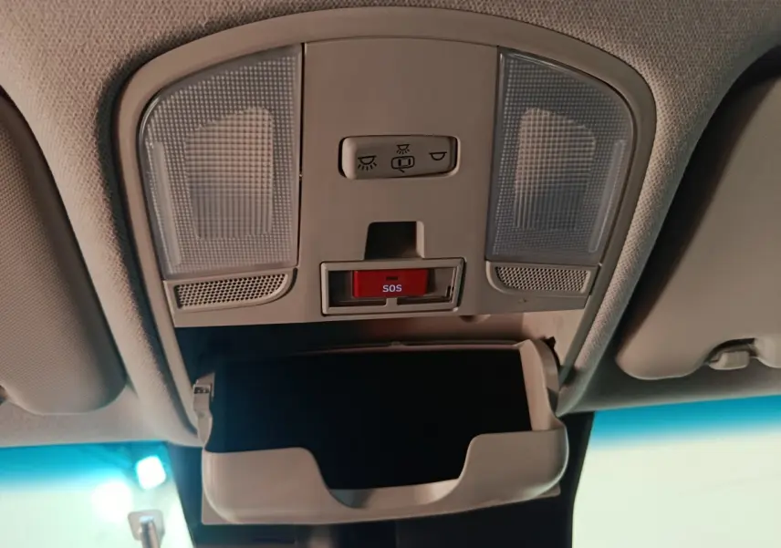 Vue intérieure du plafonnier avant avec éclairages, bouton SOS rouge et rangement lunettes ouvert dans une Hyundai Kona bleu électrique.