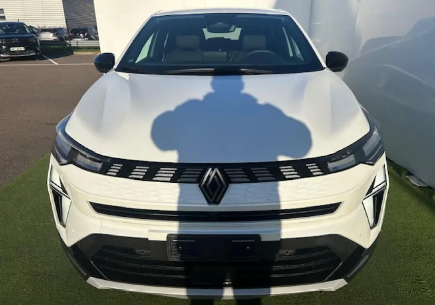 Vue avant d'une Renault Symbioz blanc nacré avec calandre noire et logo central, éclairage LED distinctif.