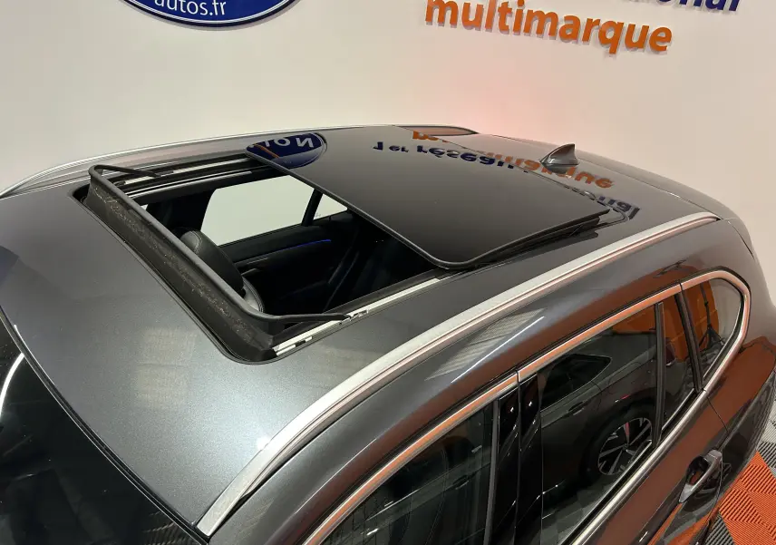 Vue plongeante sur le toit ouvrant ouvert d’un BMW X1 gris métallisé, avec détails chromés autour des vitres.
