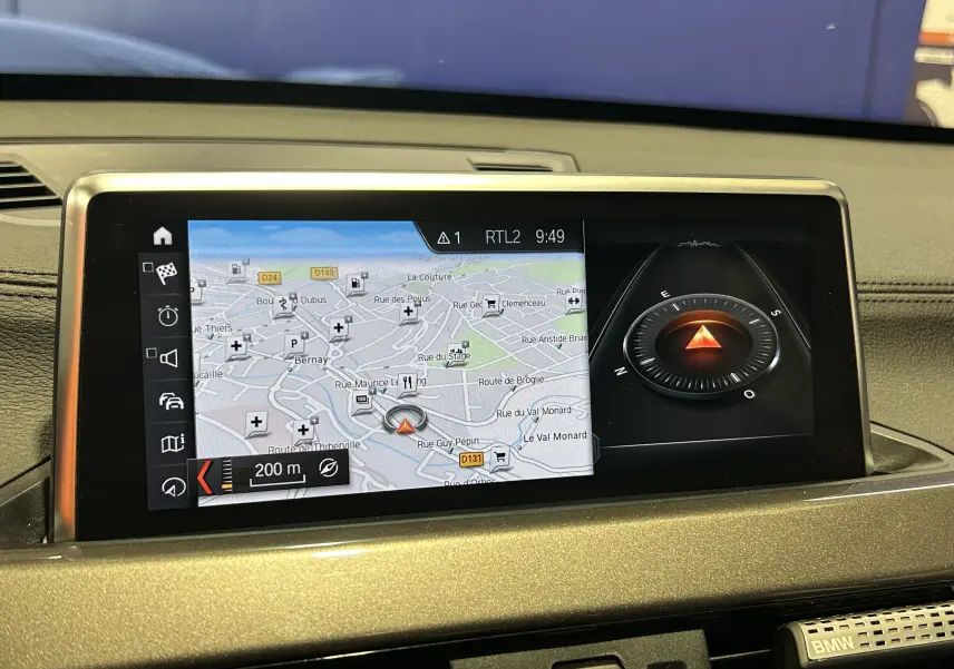 Écran central du tableau de bord du BMW X1 gris 2021 affichant la navigation avec carte et boussole digitale.