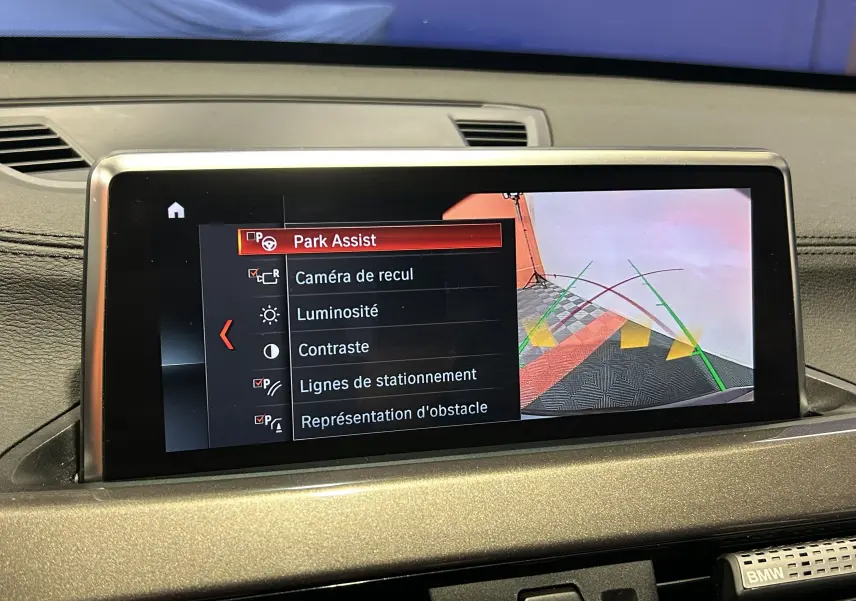 Écran central de BMW X1 2021 gris montrant les réglages du Park Assist et la caméra de recul en vue arrière.