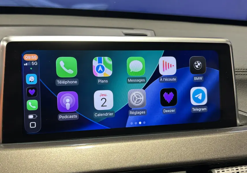 Écran tactile central de BMW X1 gris 2021 affichant les applications Apple CarPlay en intérieur véhicule.