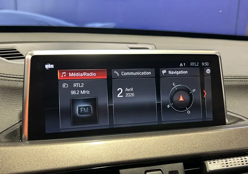 Écran central de la BMW X1 gris 2021 affichant les menus Média/Radio, Communication et Navigation en vue rapprochée.
