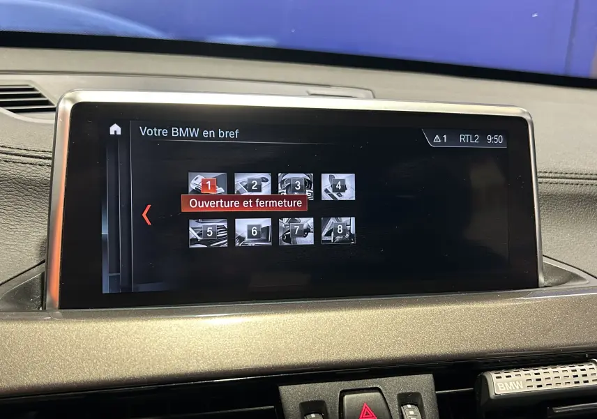 Écran central du tableau de bord d'une BMW X1 gris, affichant le menu "Ouverture et fermeture" en intérieur.