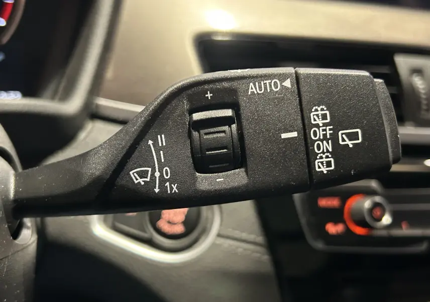 Gros plan sur la commande des essuie-glaces à gauche du volant dans l’habitacle d’un BMW X1 gris de 2021.