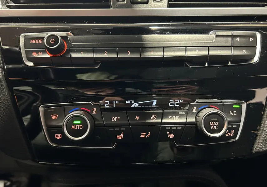 Tableau de bord de BMW X1 2021 montrant les commandes de climatisation automatique et radio en gros plan.