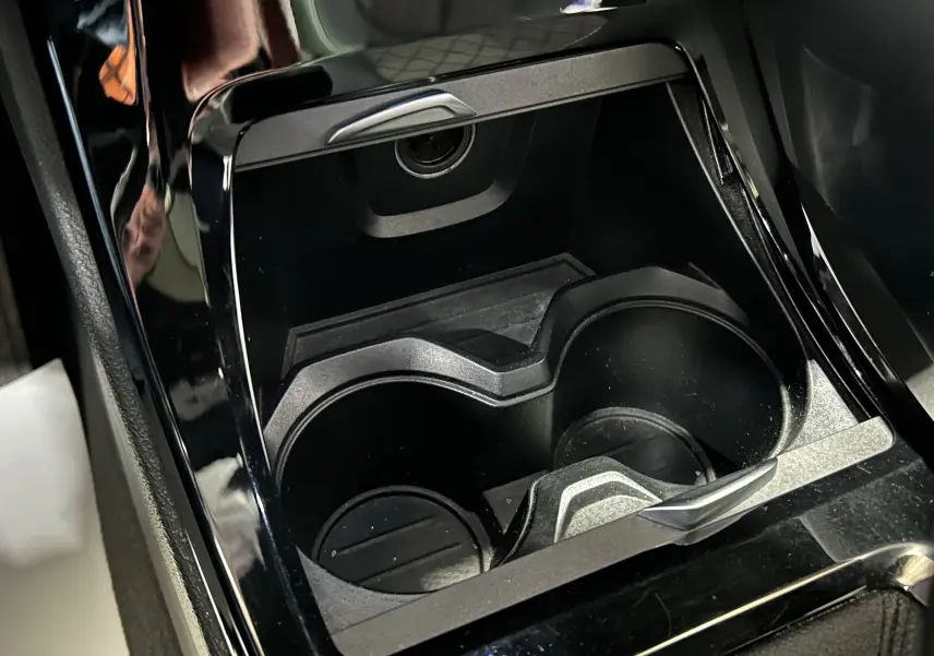 Gros plan sur les porte-gobelets noirs et la console centrale brillante d’un BMW X1 gris, intérieur moderne.