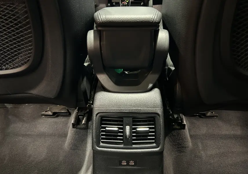 Vue rapprochée de la console centrale arrière noire avec bouches d’aération et ports USB dans un BMW X1 gris.