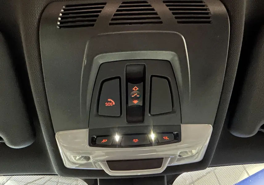 Vue en contre-plongée du panneau de commandes du toit ouvrant et éclairage intérieur du BMW X1 gris 2021.