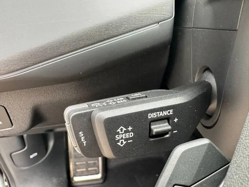 Gros plan sur la commande de régulateur de vitesse du volant d’un Audi Q3 2.0 TDI noir Mythique, intérieur noir.