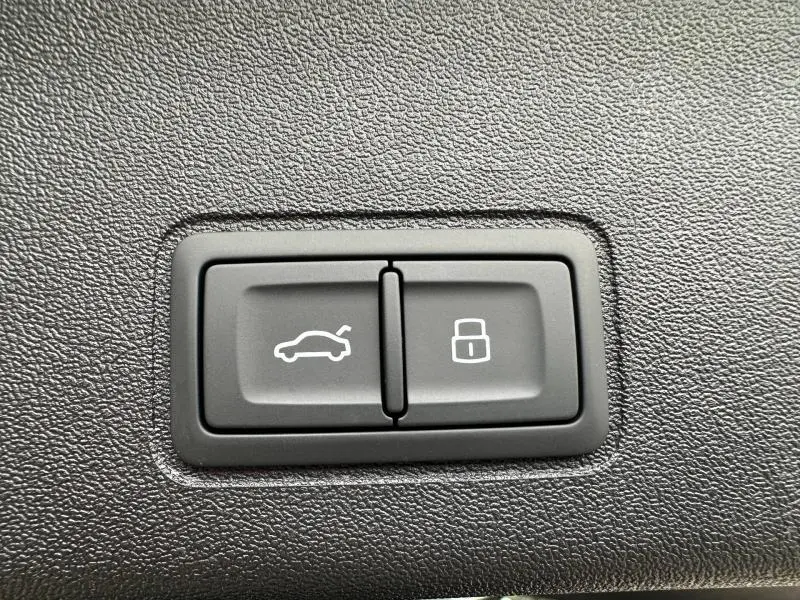 Boutons de commande du coffre et du verrouillage intérieur sur un Audi Q3 2.0 TDI noir Mythique métallisé, vue rapprochée.