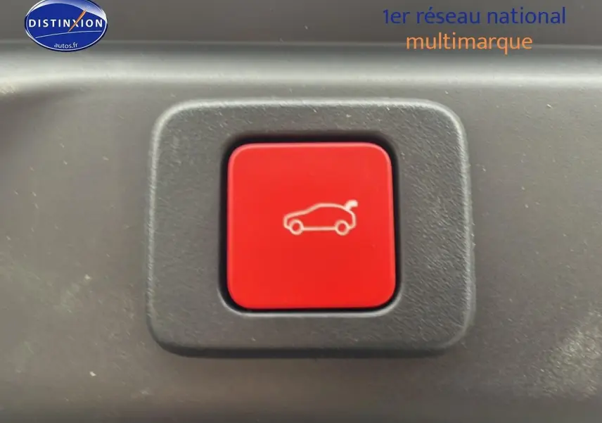 Bouton rouge de déverrouillage du coffre sur fond noir à l'intérieur du Peugeot 3008 blanc 2025.