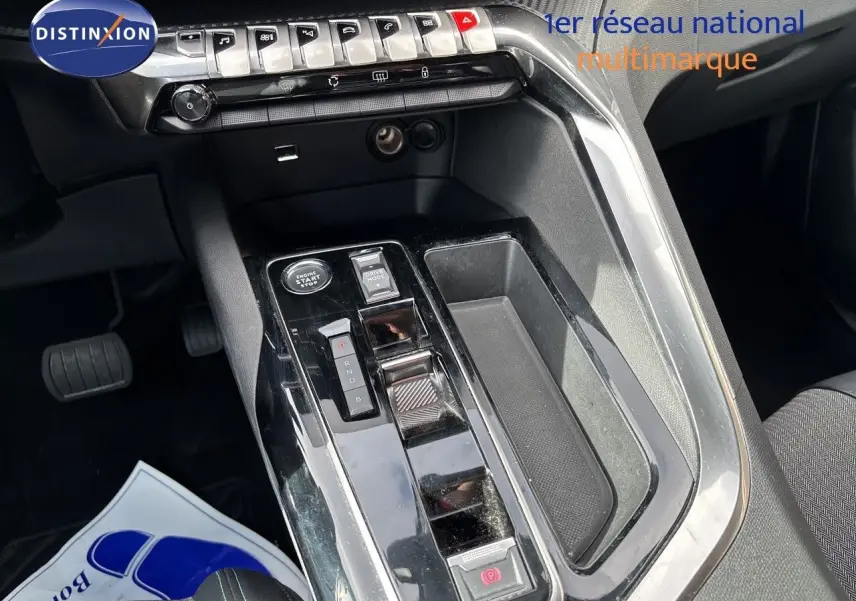 Vue rapprochée de la console centrale du Peugeot 3008 Hybrid 2024 avec commandes de boîte auto et finition noire brillante.